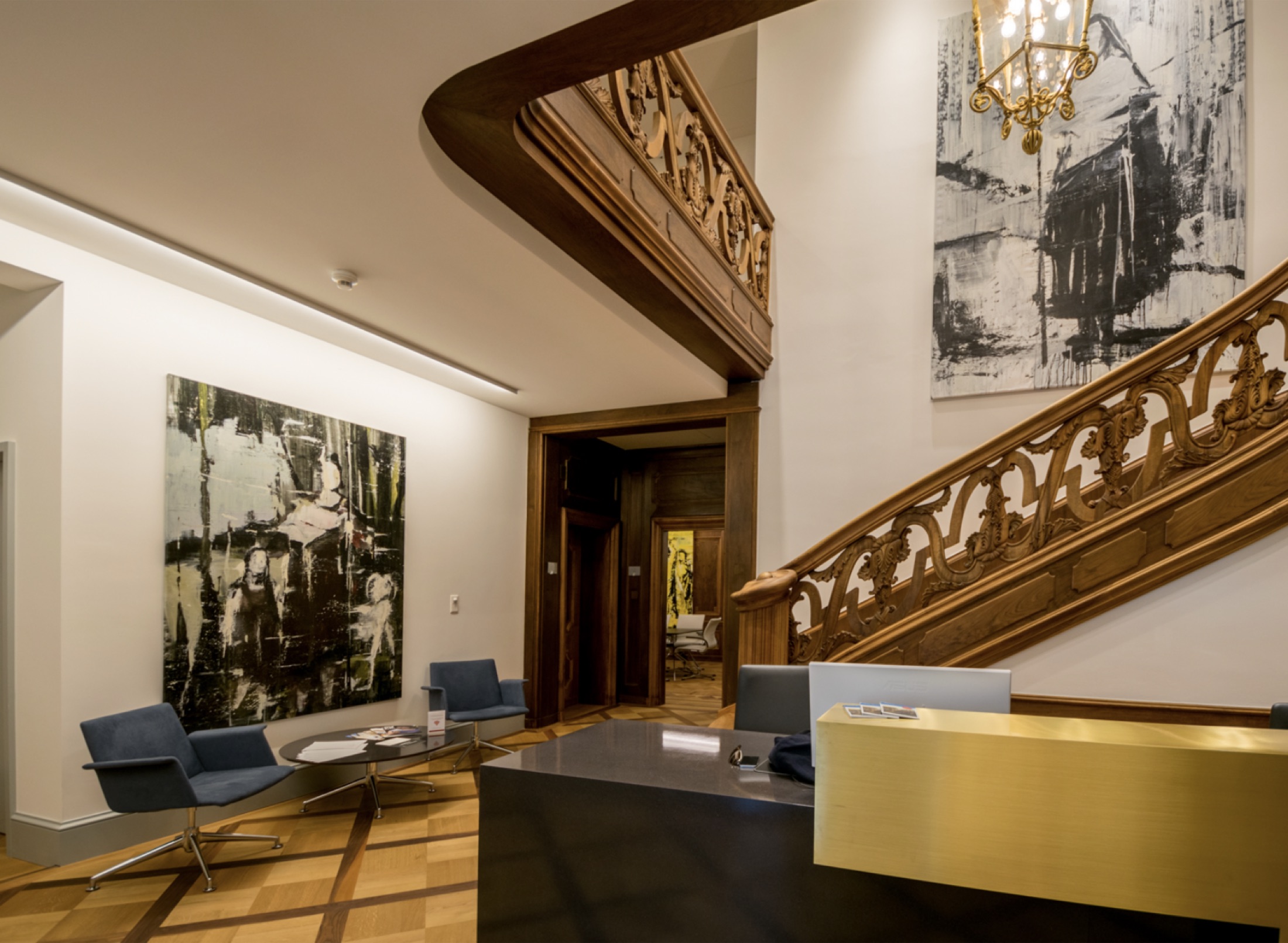 Reception of the Media Experts office in Zurich: carved wooden staircase, brass desk and large paintings.